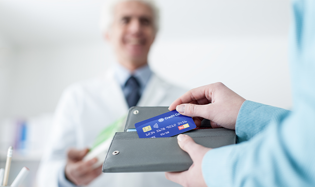 patient holding credit card with doctor in background 